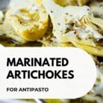 Close up of marinated artichokes plied onto a plate.