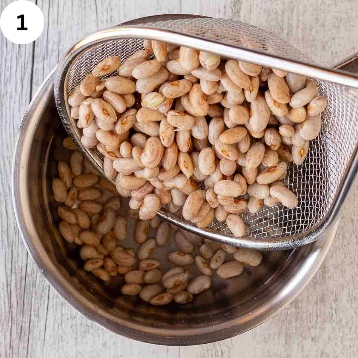 Borlotti beans in a sieve being poured into a saucepan of water.