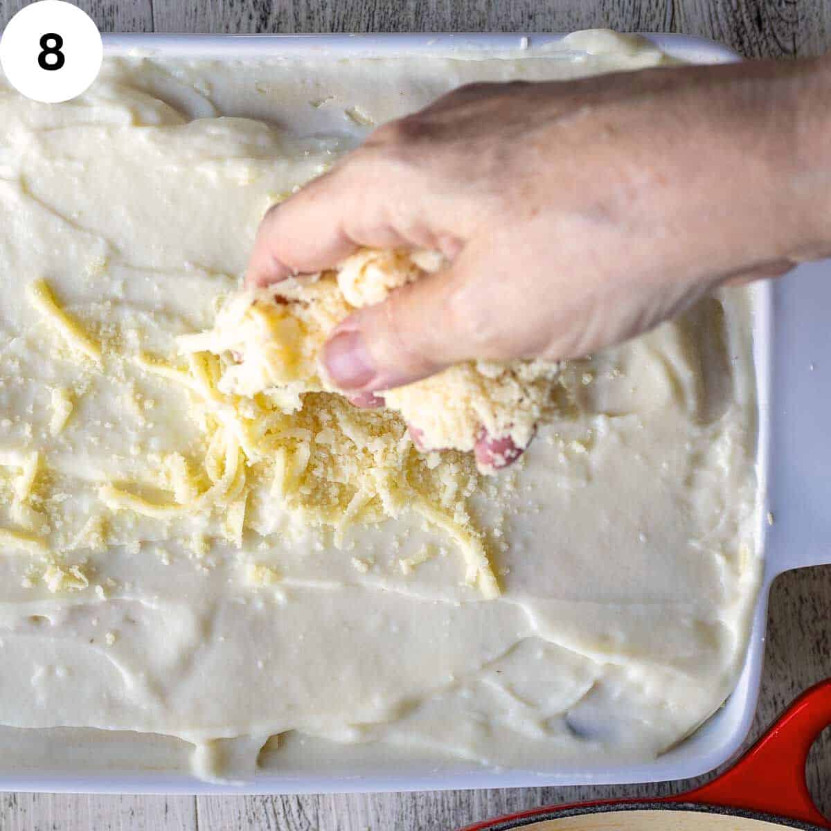 Topping uncooked lasagna with cheese before baking.