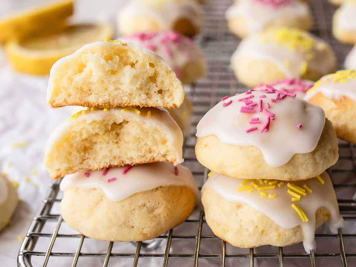 Iced cookies piled one on top of the other with two cookie broken in half to reveal the inside.