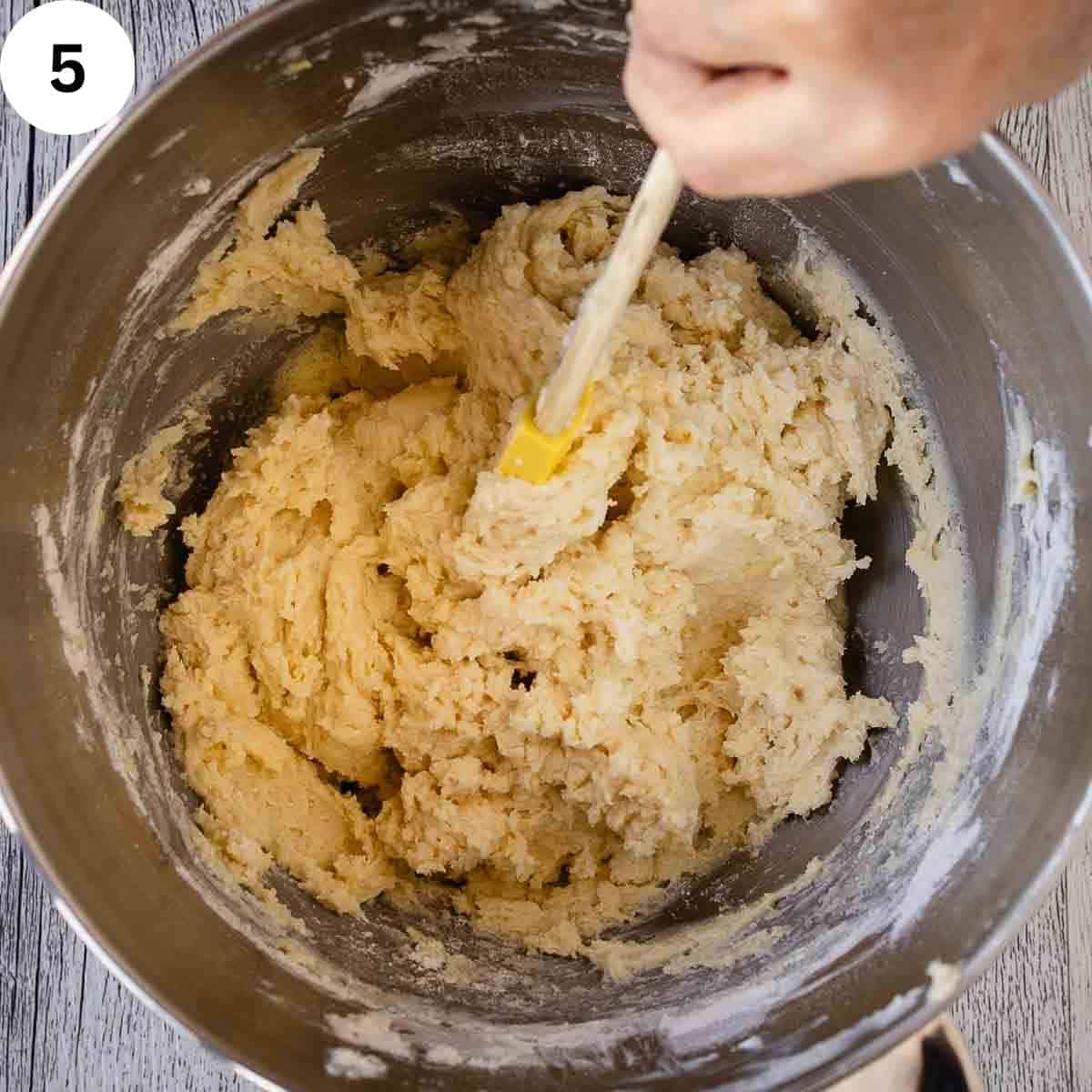 Stirring soft cookie dough in a stainless steel bowl.