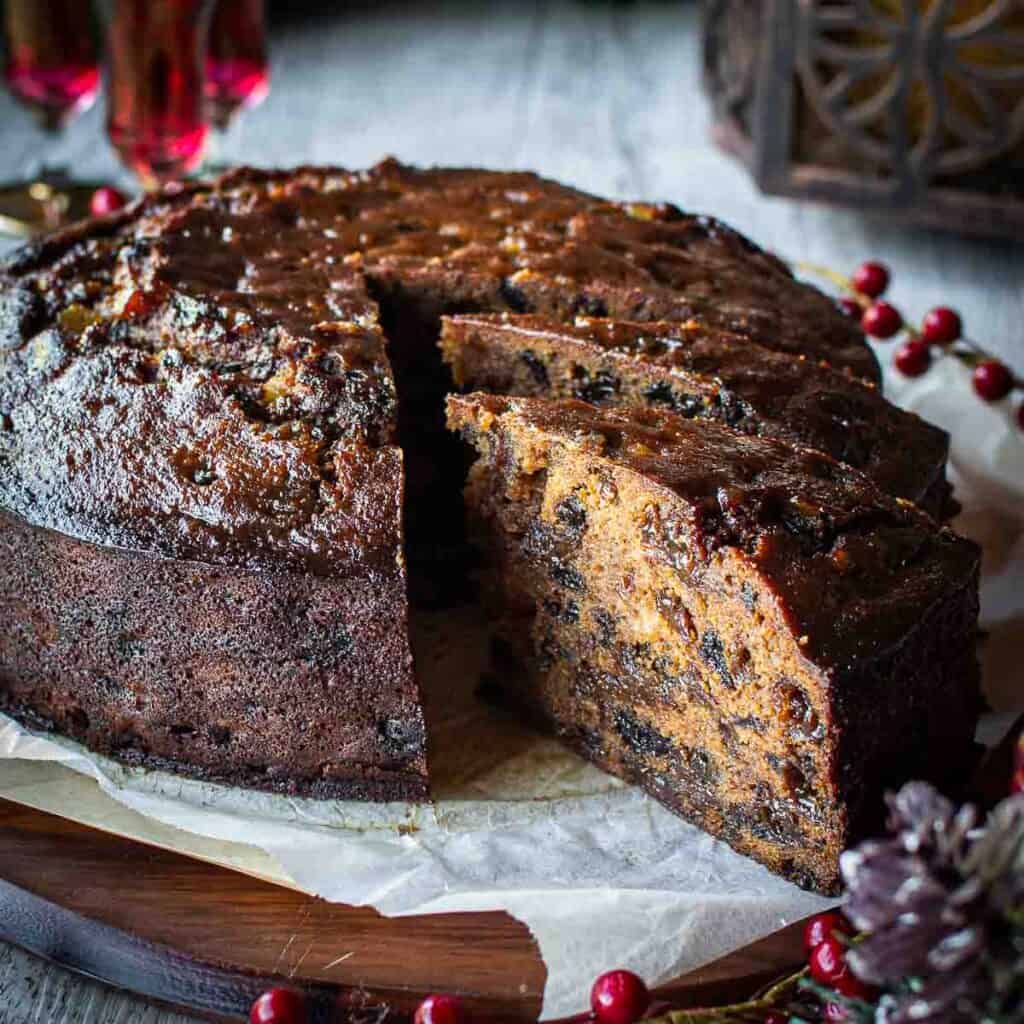 A round Rum Fruit Cake with a two slices cut and pulled out to show the inside of the cake.