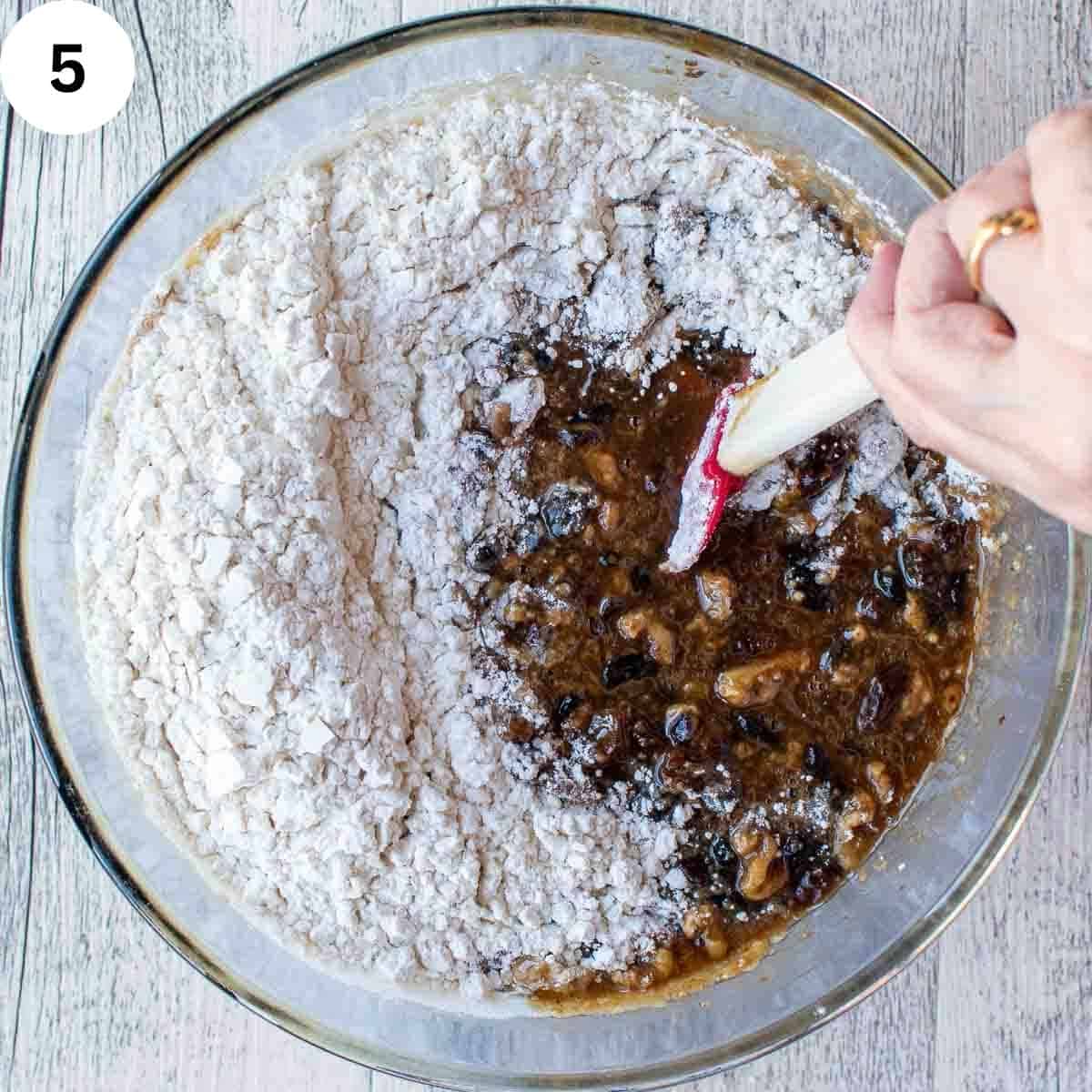 Flour being stirred into dried fruit mixture for fruit cake.