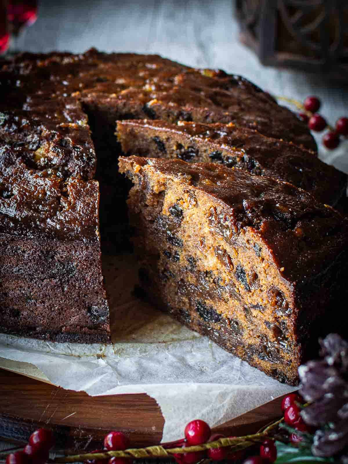 A round Rum Fruit Cake with a two slices cut and pulled out to show the inside of the cake.