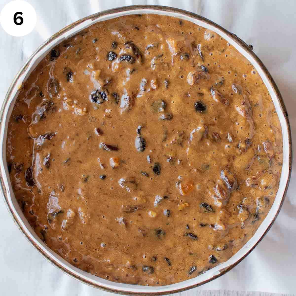 Uncooked fruit cake batter in a round cake pan.