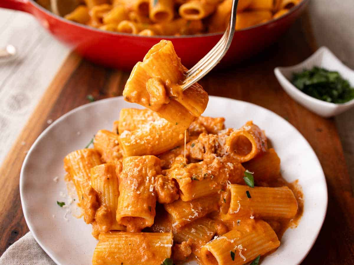 Rigatoni pasta with creamy tomato sauce on a plate with a few pieces of pasta speared onto a fork.