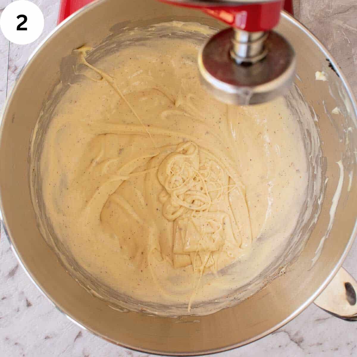 Thick batter with flecks of vanilla through it in a stainless steel bowl.