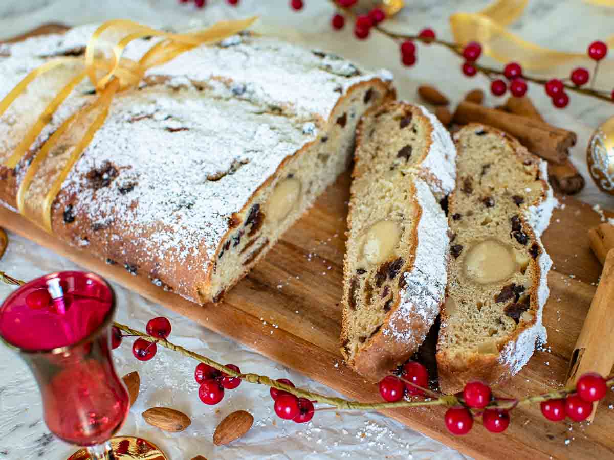 Christmas stollen on a wooden board with three slices cut.