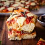 Two squares of Anchovy Pizza stacked on top of one another.