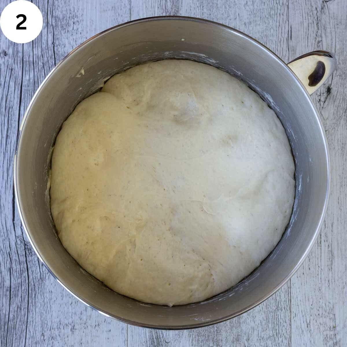 Proofed yeasted dough in a stainless steel bowl.