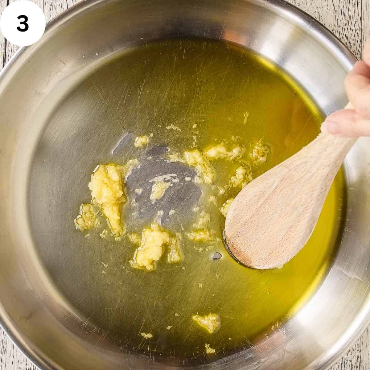 Stirring minced garlic with olive oil in a pan.