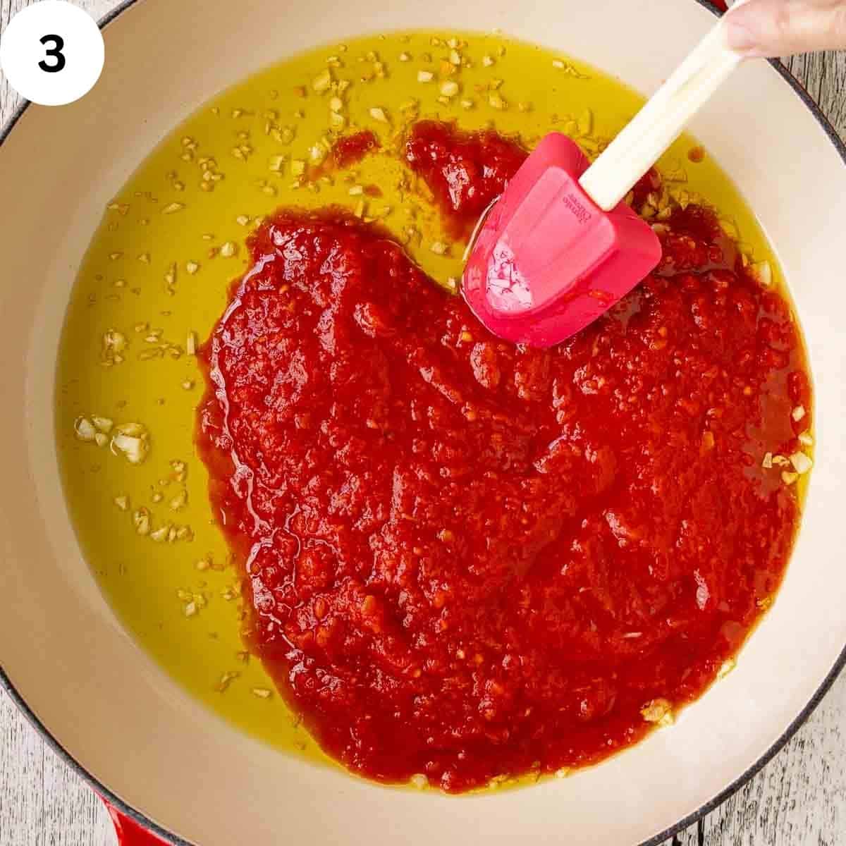 Stirring tomato puree and olive oil in a pan.