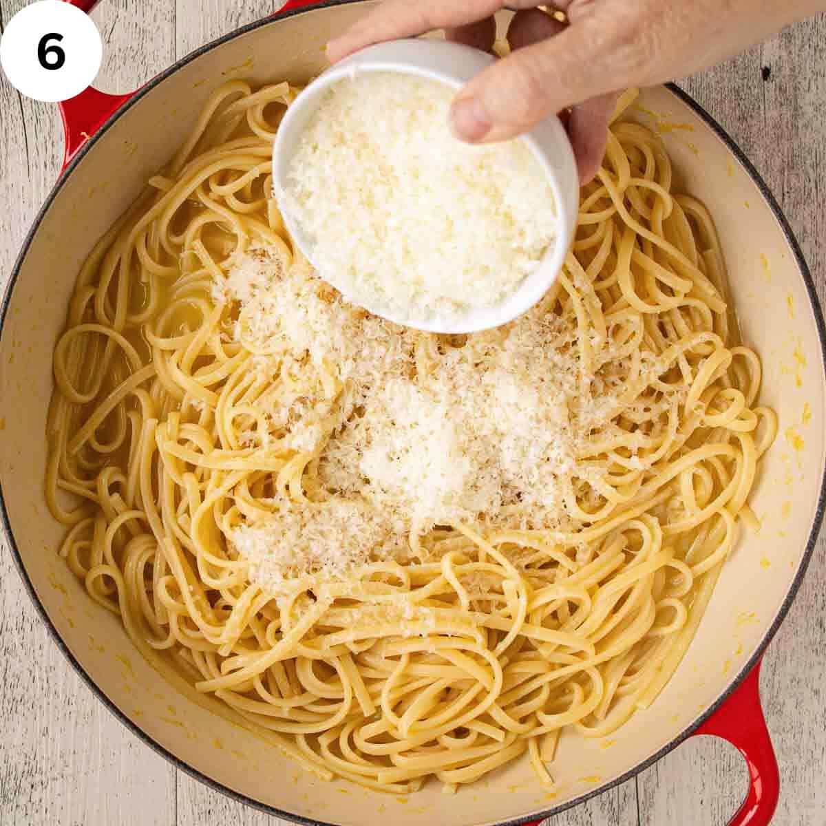 Adding finely grated Parmesan cheese to linguine pasta.