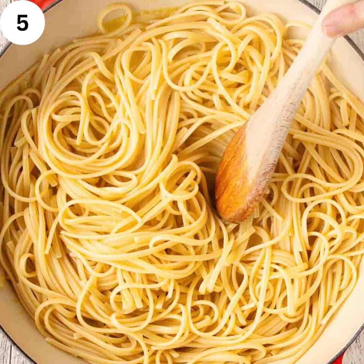 Stirring linguine pasta with a wooden spoon.