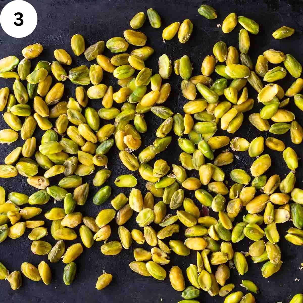 Peeled pistachios on a baking sheet.
