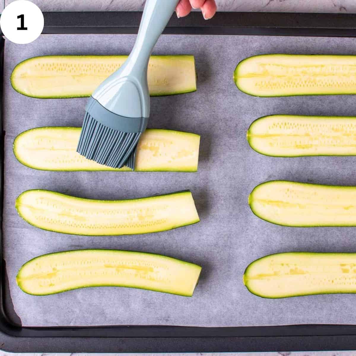 Brushing upturned zucchini halves with oil.
