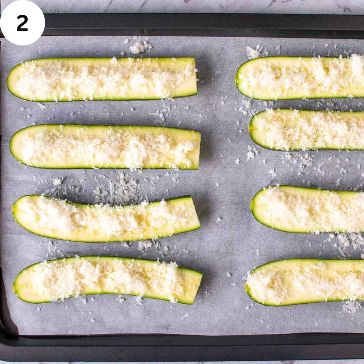 Finely grated parmesan cheese on upturned zucchini halves.