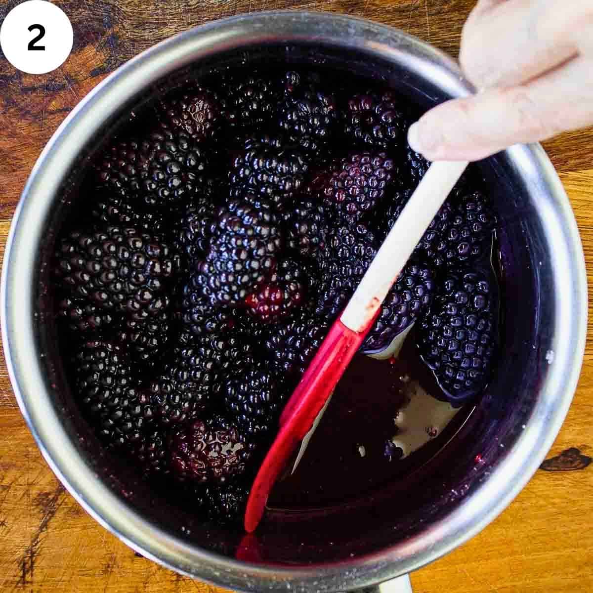 Stirring blackberries in a saucepan.