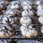 Chocolate drizzled cannoli cookies on a cooling rack.