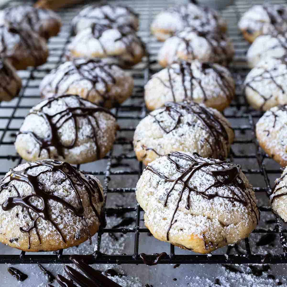 Chocolate drizzled cannoli cookies on a cooling rack.