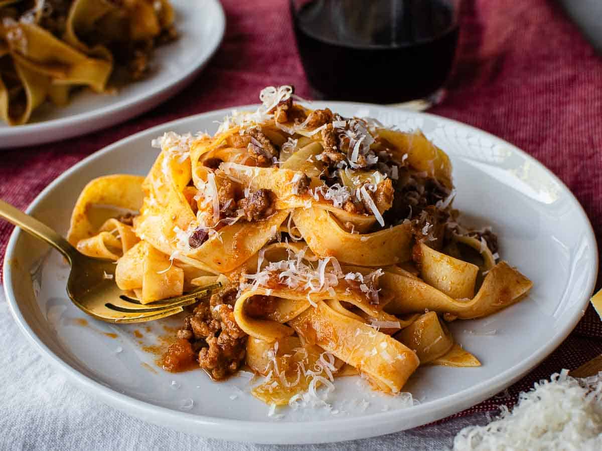 Making fresh pasta a home requires only two ingredients - flour and eggs. Learn how to make your own egg pasta with this step by step recipe. #homemade #homemadepasta #eggpasta #italianrecipe #pastarecipe Tagliatelle with traditional Bolognese sauce on a plate.