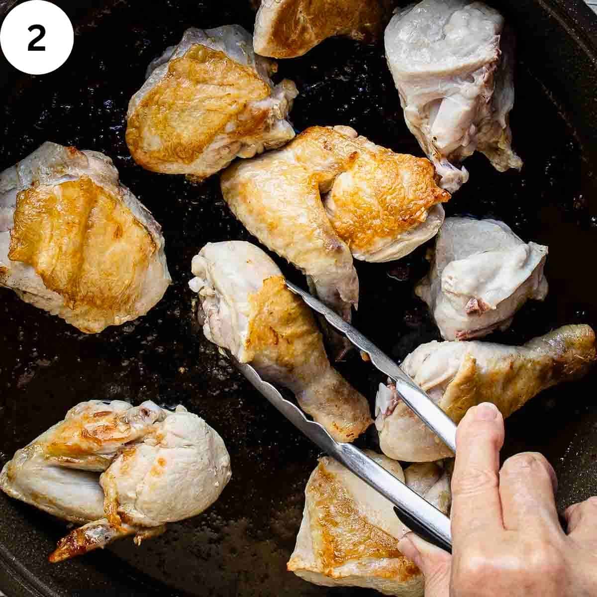 A person frying chicken pieces in a pan.