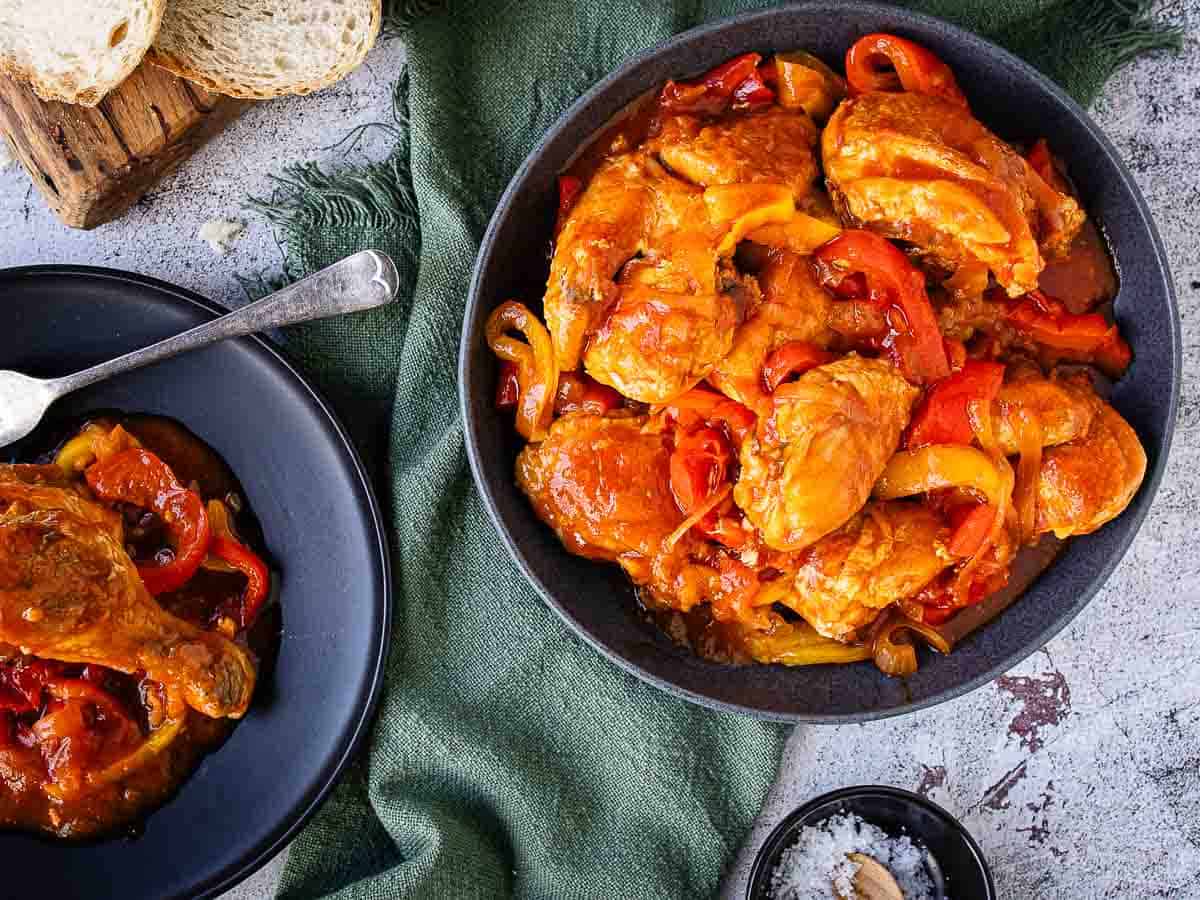 Chicken and peppers served in a nice round bowl with a serving separated on a plate.