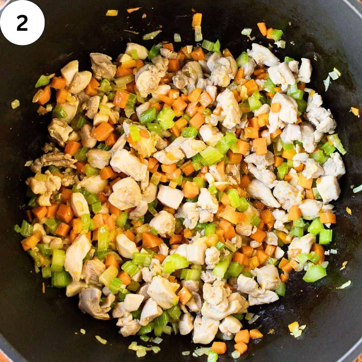 Chopped boneless and skinless chicken and diced mixed vegetable in a saucepan.