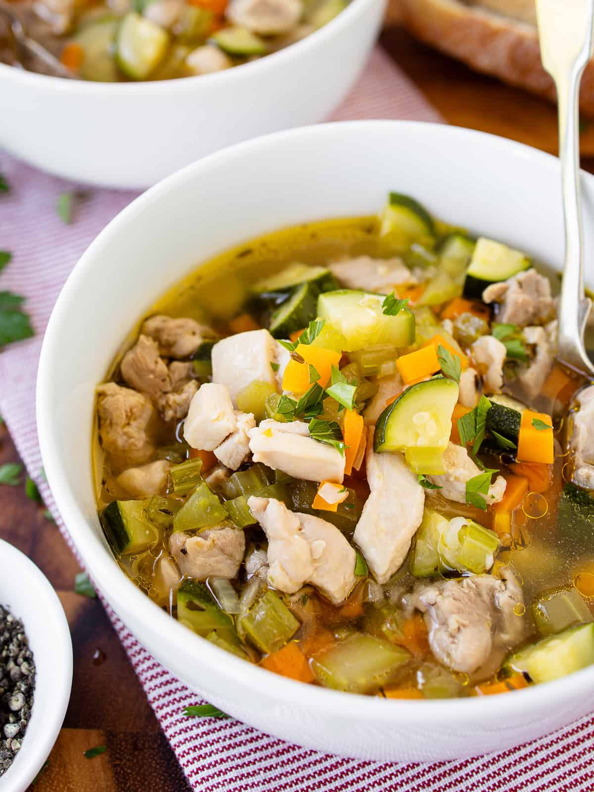 A bowl of chicken vegetable soup with bread.