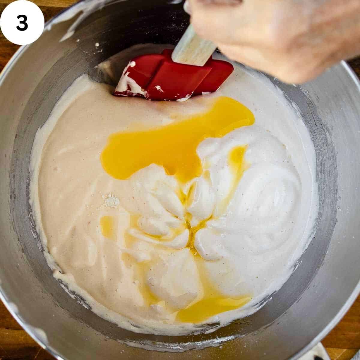 Using a spatula to fold melted butter into a batter.