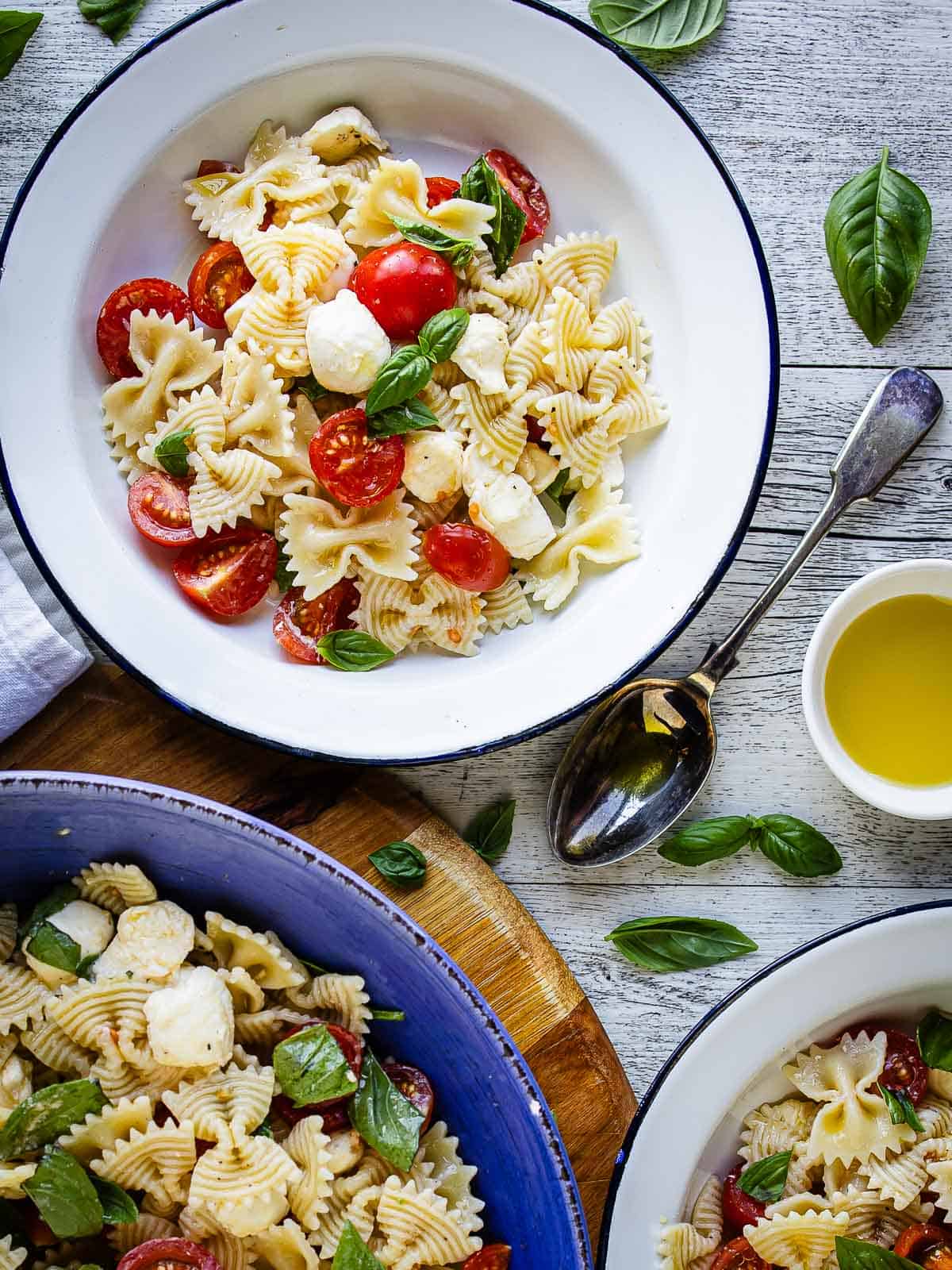 Pasta salad with tomatoes and bocconcini in bowls viewed from above.