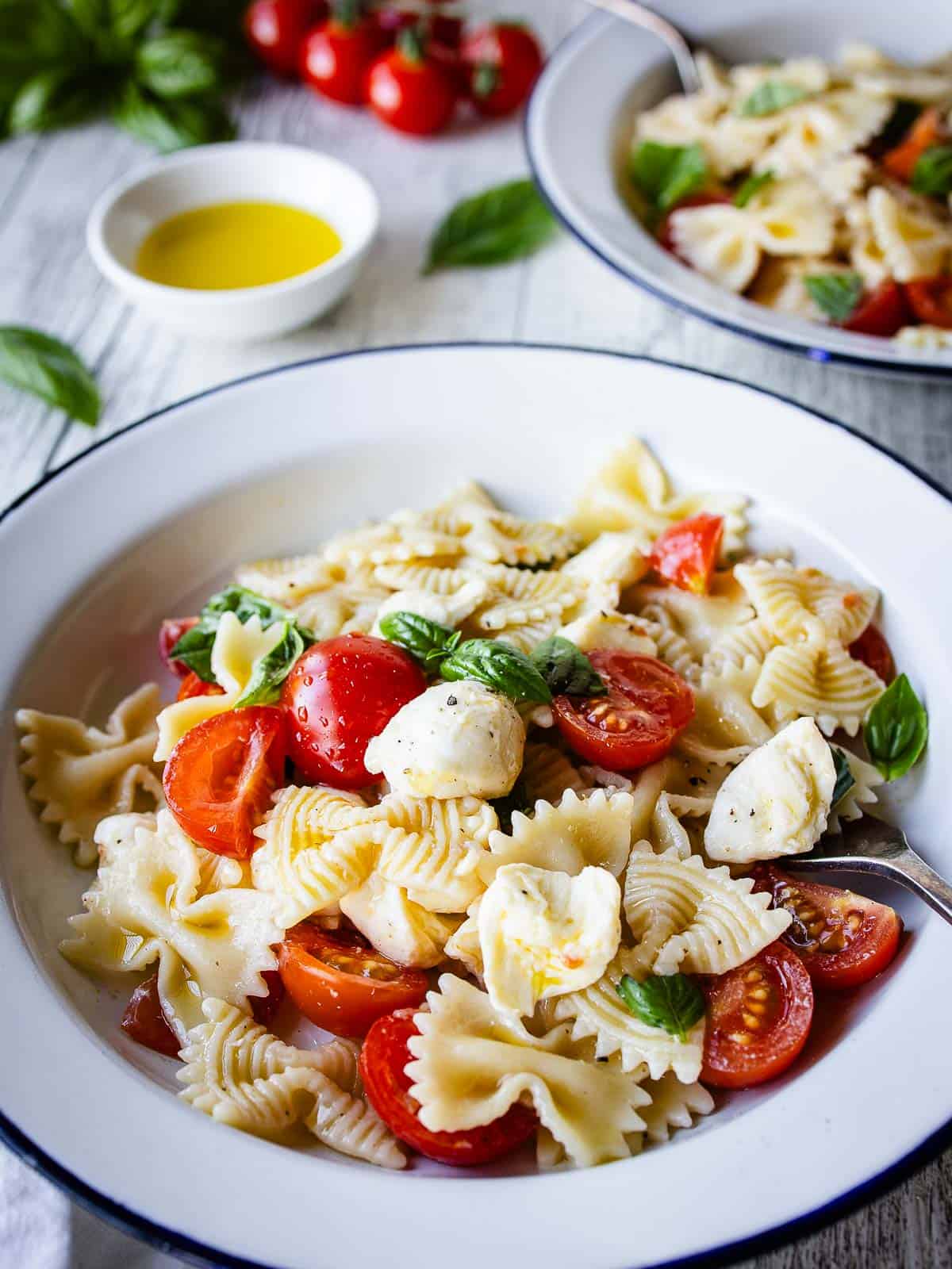 Caprese Pasta Salad in a bowl with another bowl in the background.