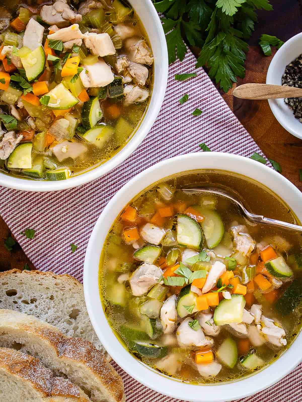 Two bowls of vegetable and chicken soup viewed from above.