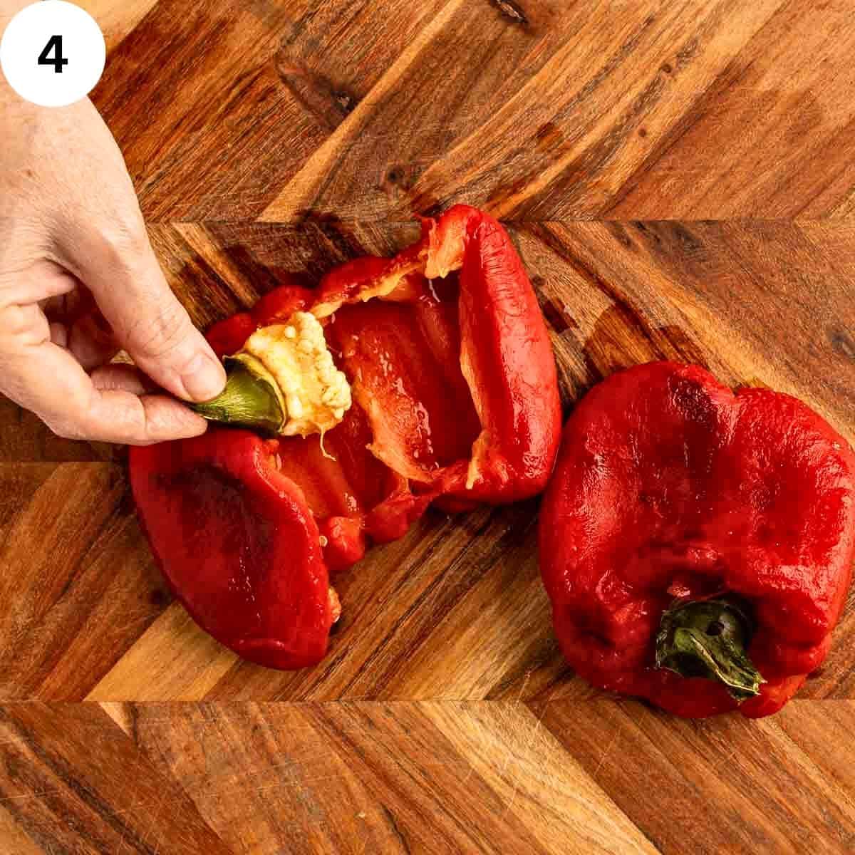 Removing the stalk and seed core from roasted peppers that have be cut open.