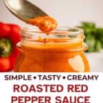 Jar of roasted red pepper sauce with a spoon taking a scoop.