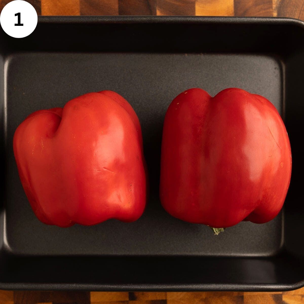 Two red peppers in a baking pan.