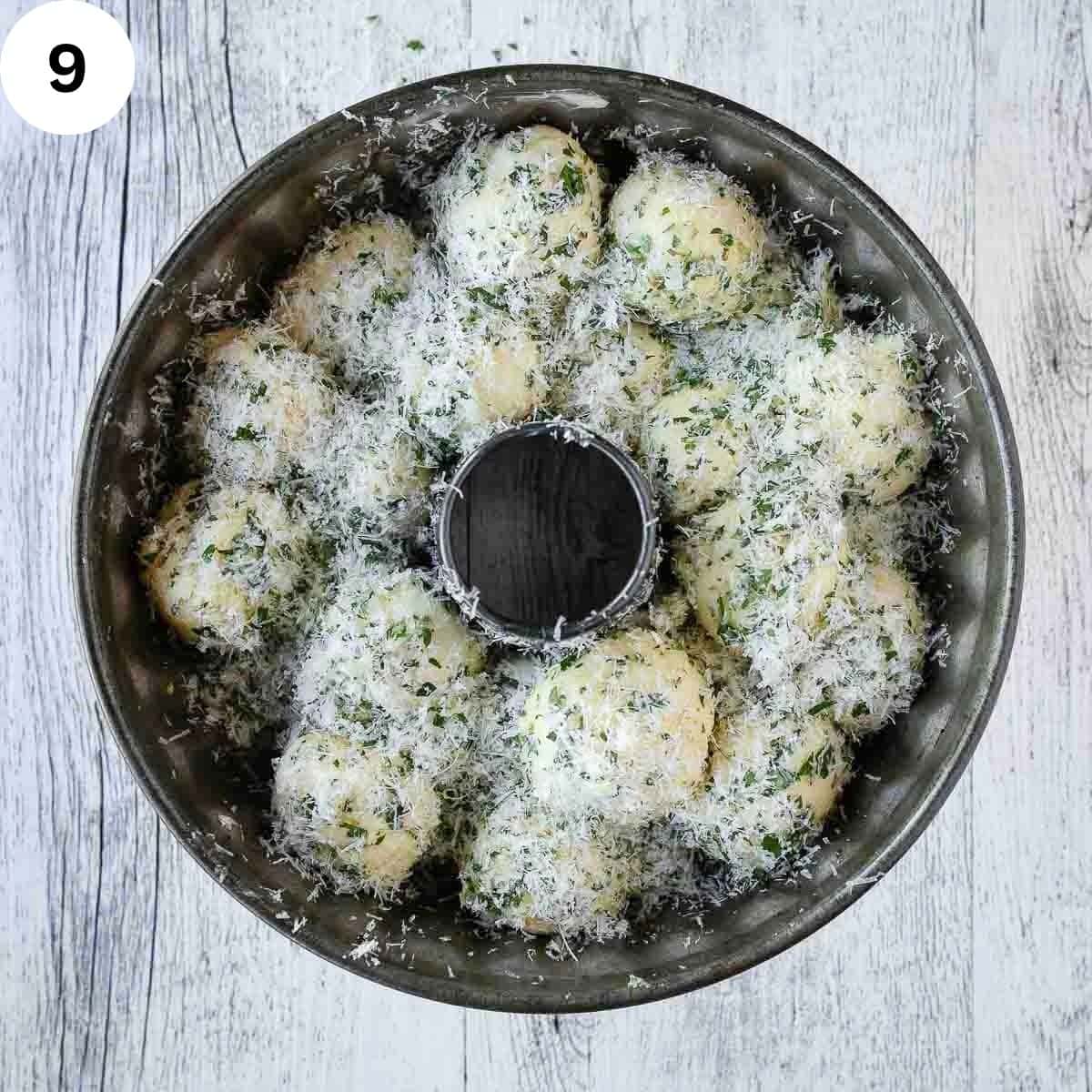 Dough balls coated into Parmesan cheese and herbs arranged in a bundt pan.