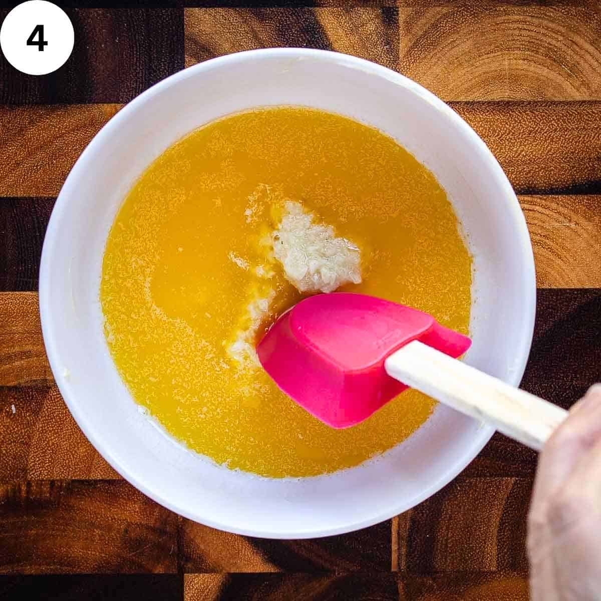 Mixing minced garlic into melted butter.