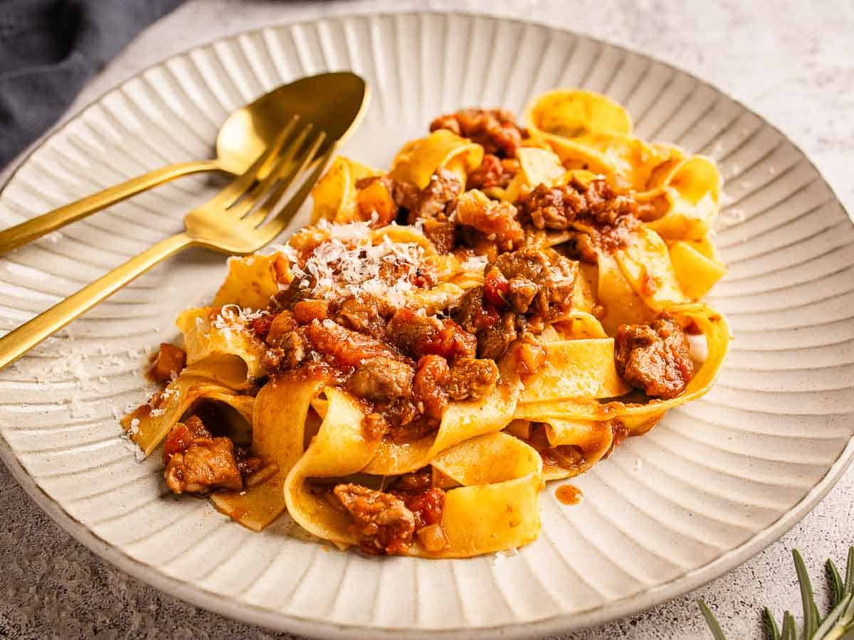 Plated pappardelle pasta with hearty meat sauce.
