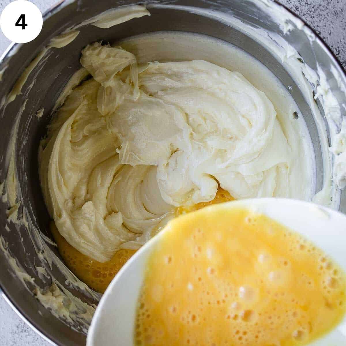 Slowly pouring beaten eggs into cream cheese mixture in bowl.