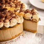 Baked tiramisu cheesecake with a slice cut and being removed on a cake server.