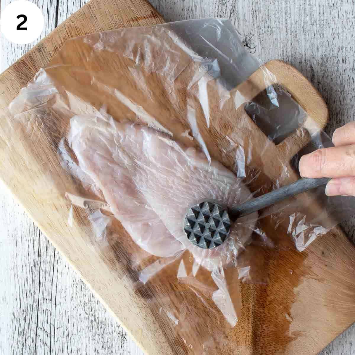 Pounding chicken breast with a meat mallet.