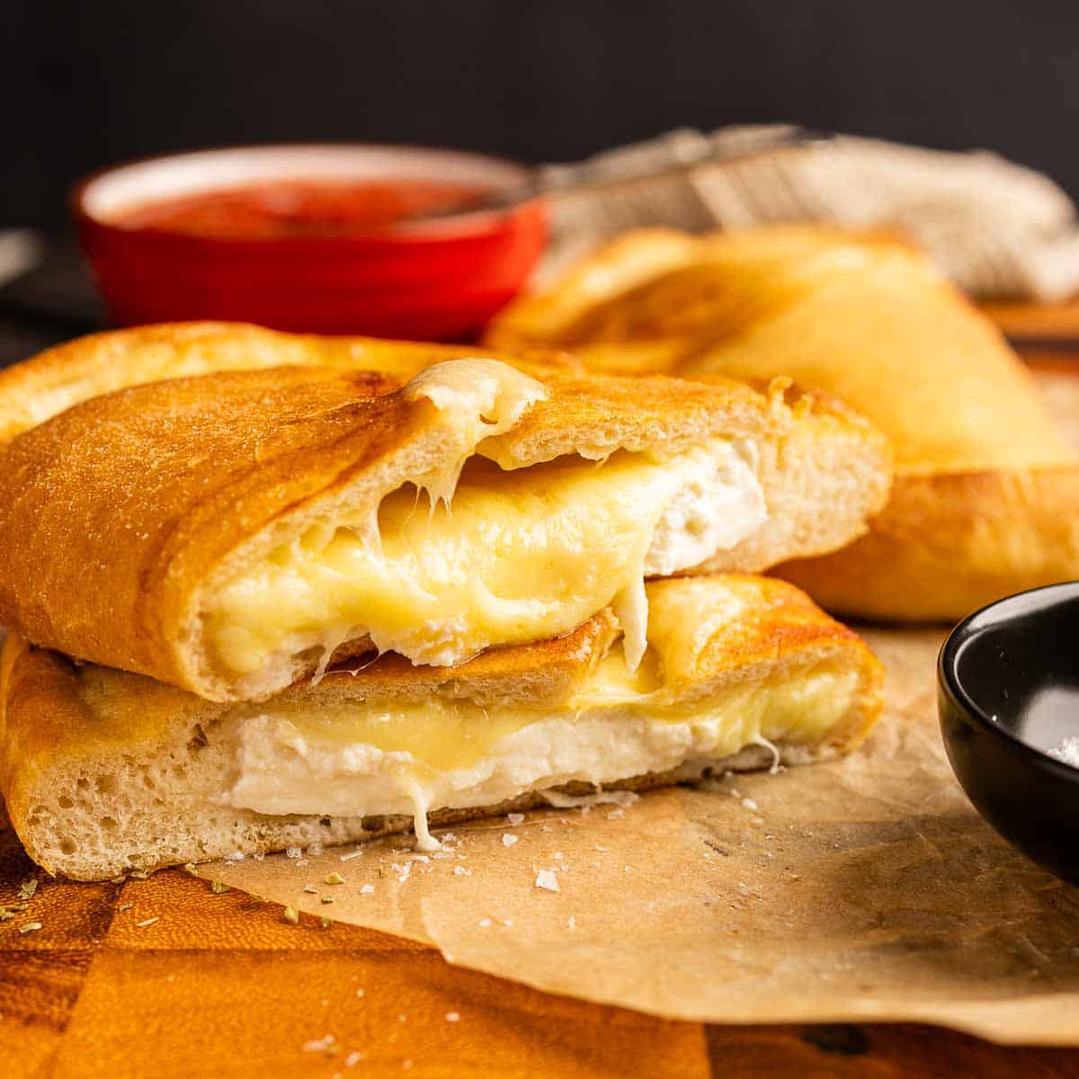 Cheese calzone cut in half and place one on top the the other half showing cheese oozing.