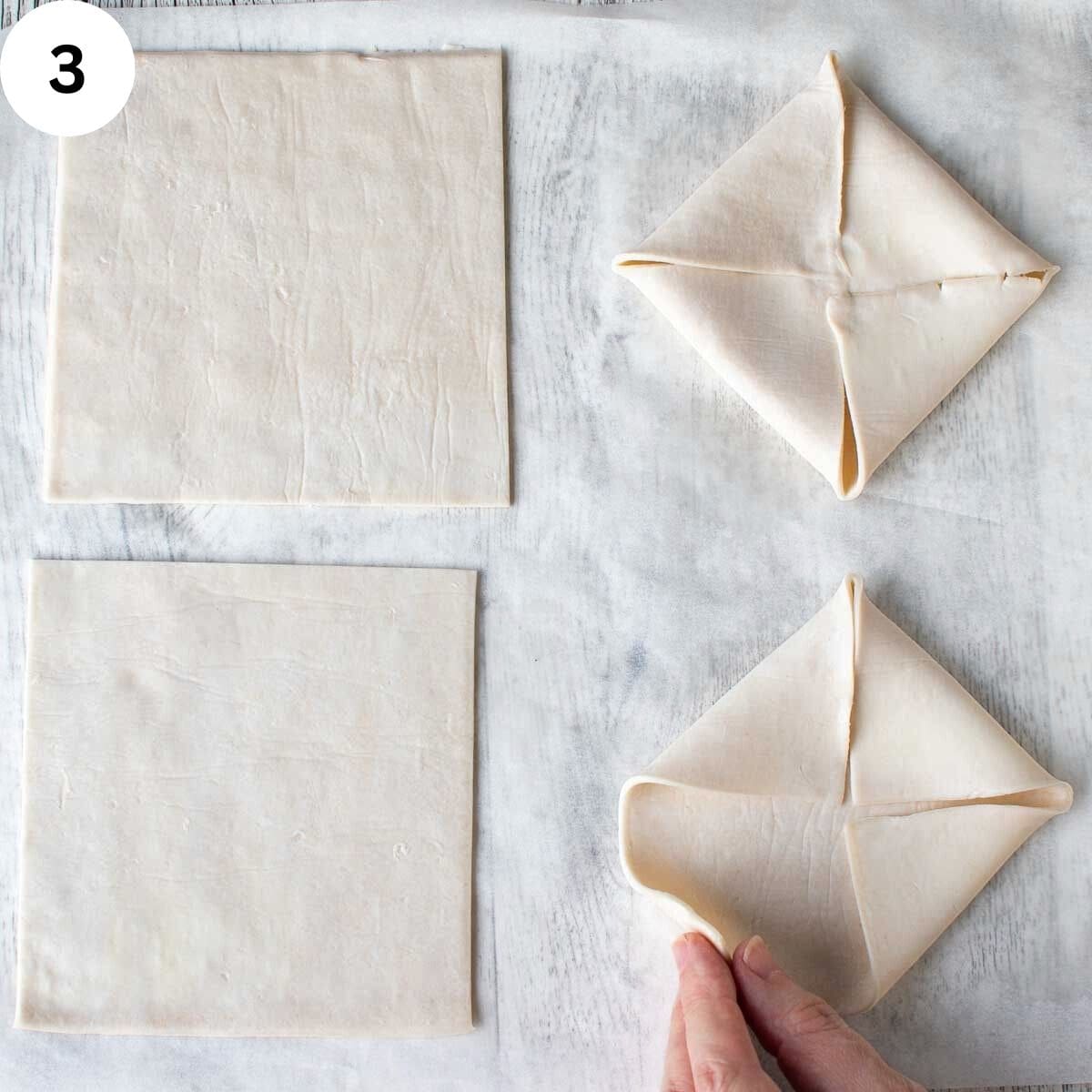 Squares of store bought pastry, one folded and the another one being folded.