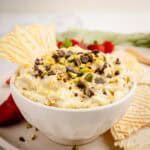 Creamy cannoli dip topped with chocolate chips and chopped pistachios and served with crispy pizzelle.