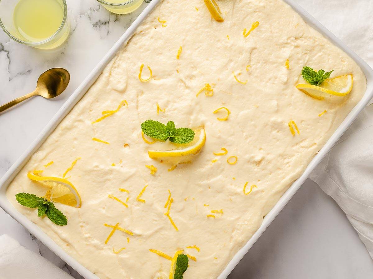 Overhead view of a creamy dessert garnished with lemon slices and mint in a rectangle serving dish.