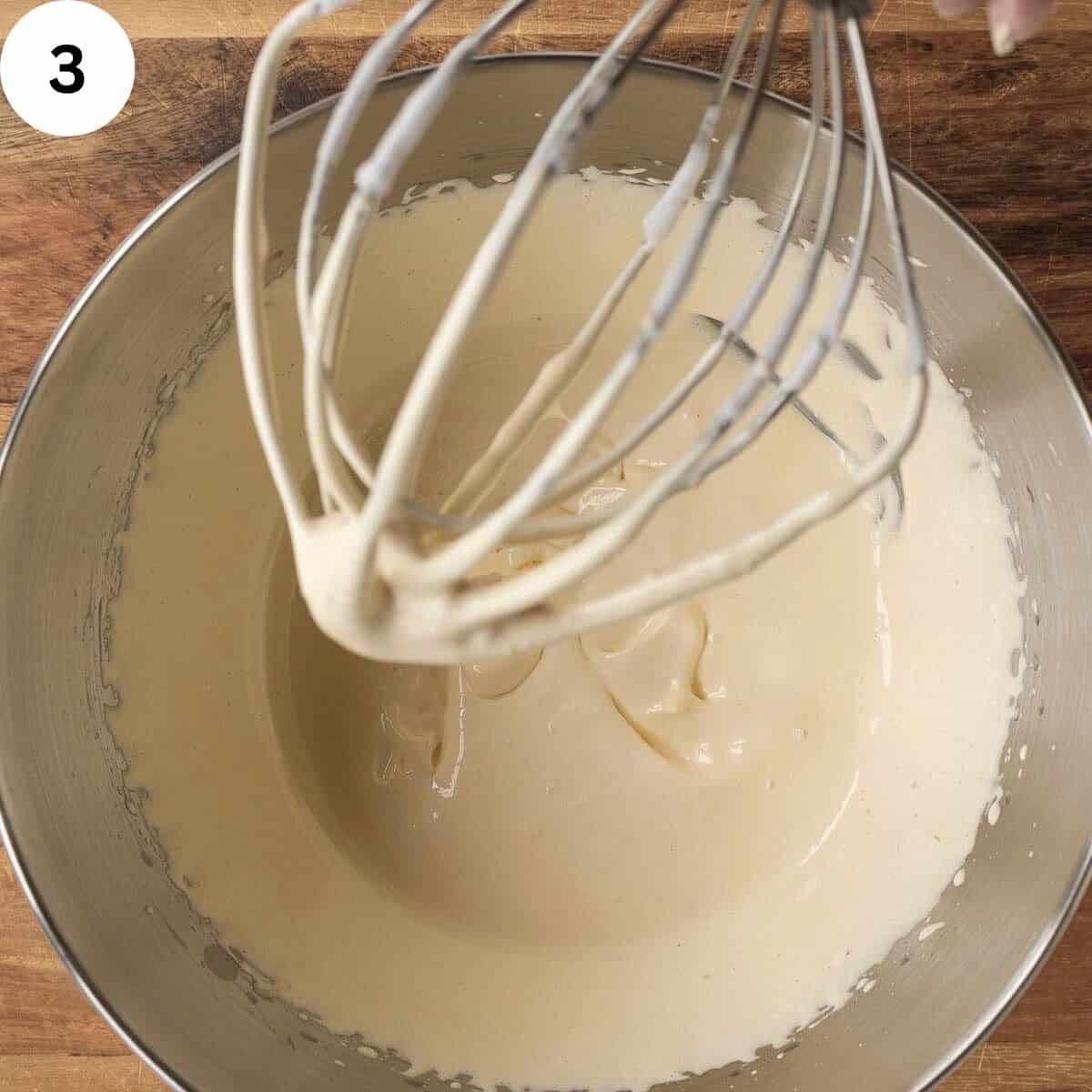 Thickened whipped egg yolk and sugar mixture in a stainless steel bowl.