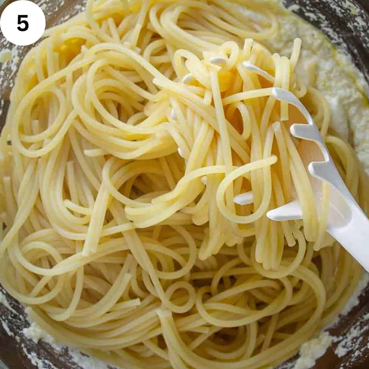 Adding cooked spaghetti to ricotta cheese mixture.