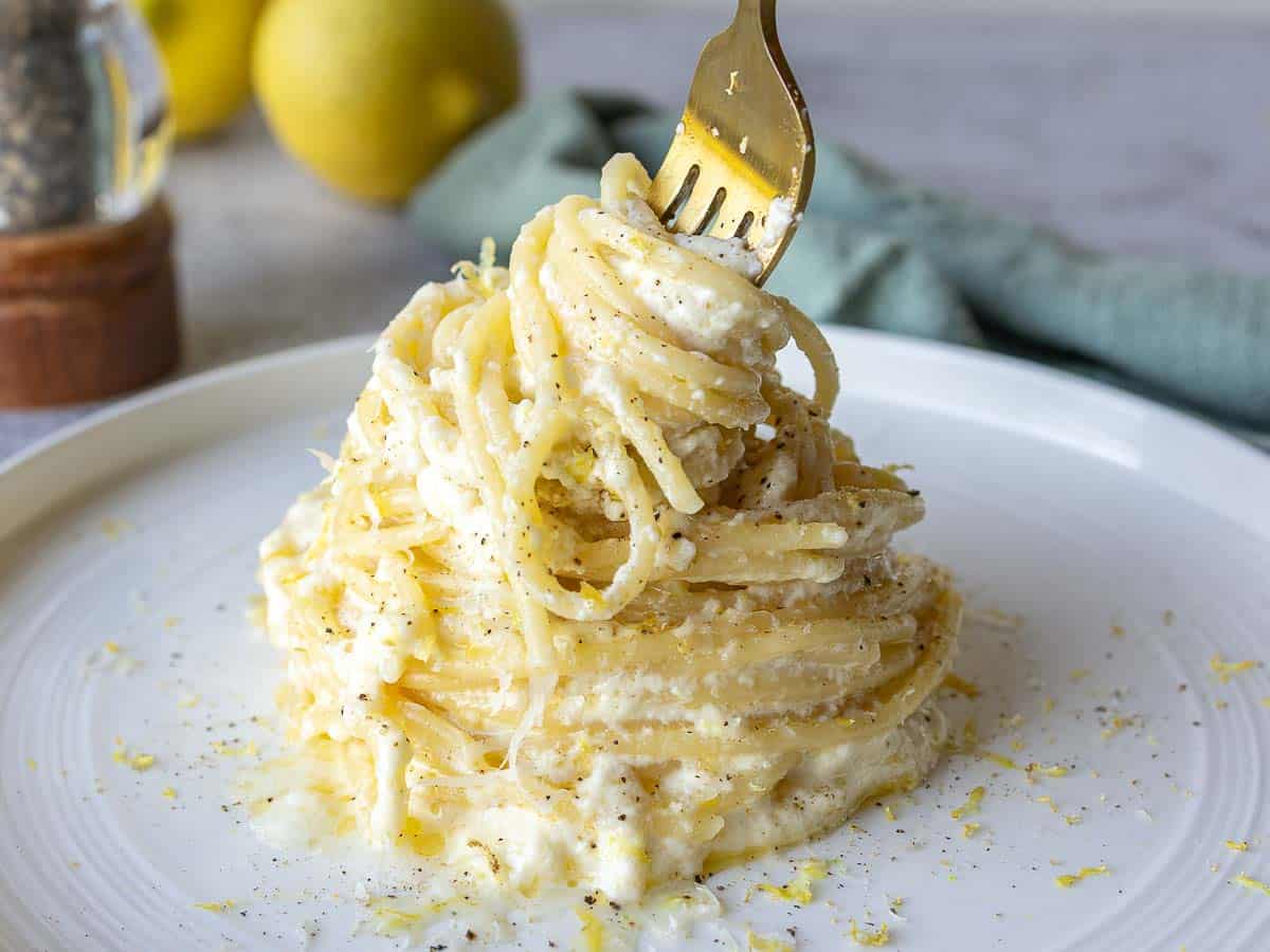 Close up of creamy spaghetti with a fork twirling some spaghetti.