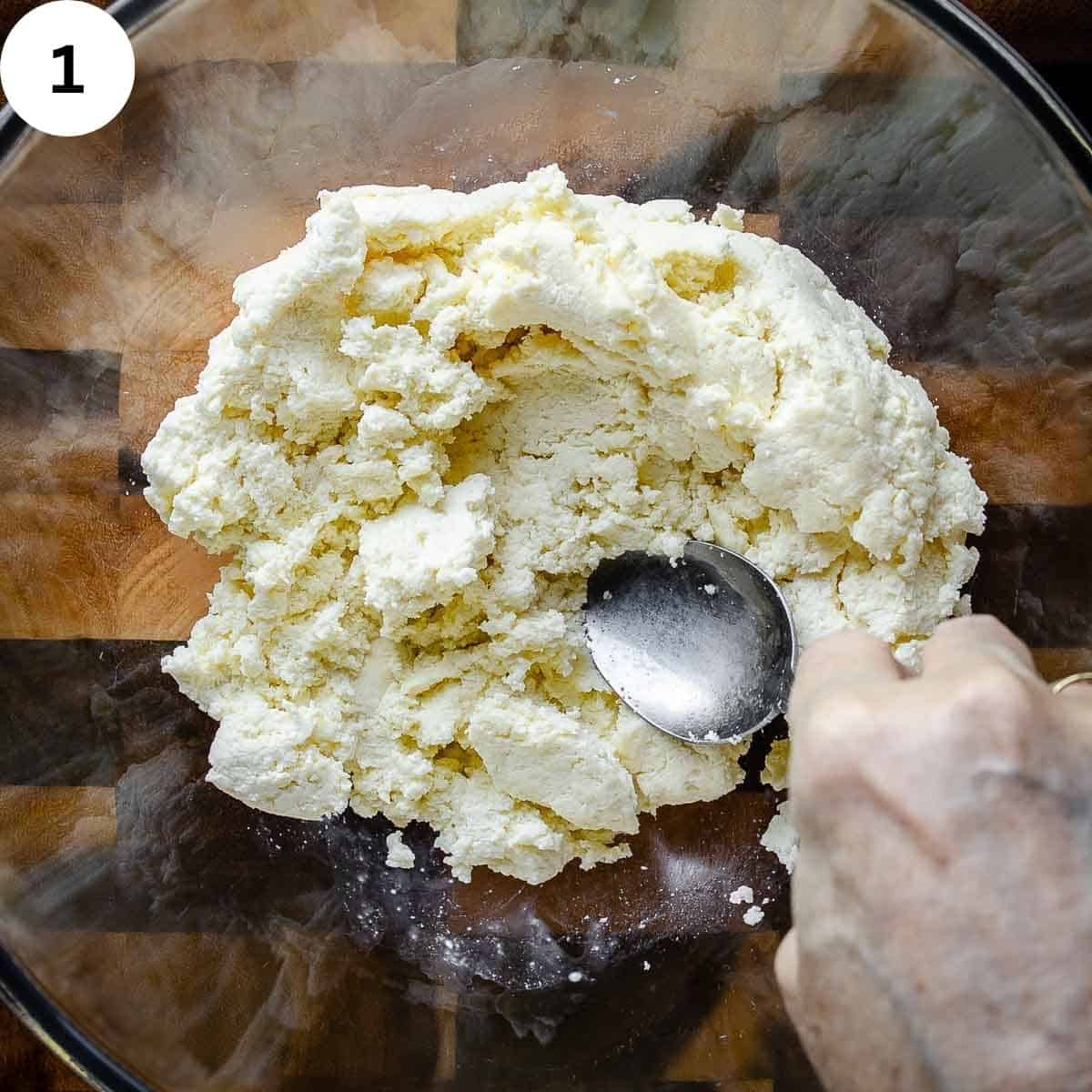 Mashing ricotta cheese with the back of a spoon.